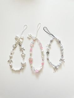 three bracelets with bows and pearls are on a white surface, one in the shape of an egg