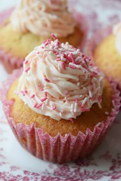 three cupcakes with white frosting and sprinkles on a plate