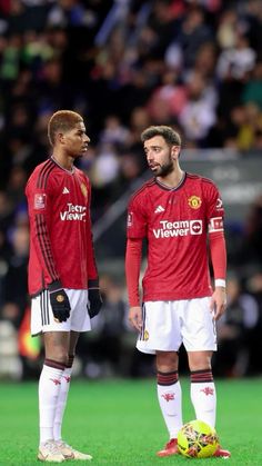 two men standing next to each other on a soccer field