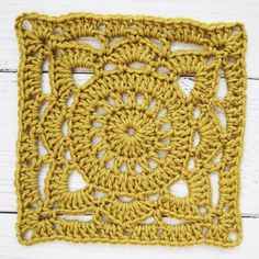 a yellow crocheted square with an intricate design