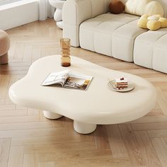 a white coffee table sitting on top of a hard wood floor next to a couch