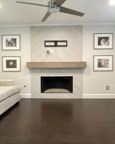 an empty living room with a fireplace and pictures on the wall above it's mantle