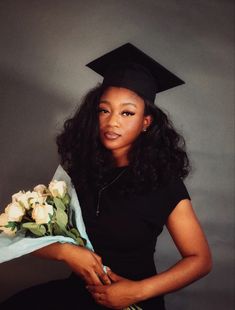 a woman in a graduation cap and gown holds flowers while posing for a photo with a bouquet of roses