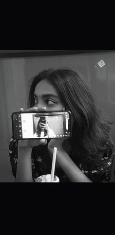 a woman taking a selfie in front of a mirror with her cell phone up to her face