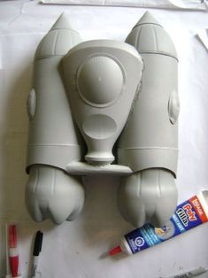 a white object sitting on top of a table next to toothbrushes and glue