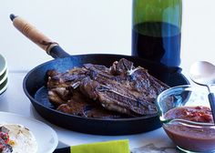 steaks and sauce in a skillet with a bottle of ketchup on the side