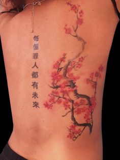 the back of a woman's body with tattoos on her chest and cherry blossoms