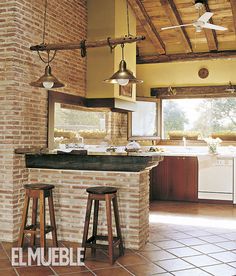 a kitchen with two stools in front of a brick wall and an island counter