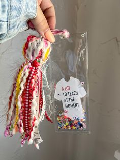 a person holding up a piece of fabric with the words alot to teach in the moment