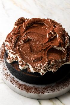 a chocolate cake with white frosting and sprinkles on a marble surface