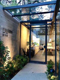 the inside of a modern house with glass walls and plants in the front garden area