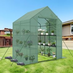 a green house with plants in it on the grass