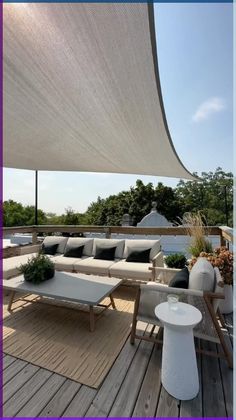 an outdoor living area with couches and tables under a large white awning on a wooden deck