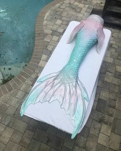 an image of a mermaid tail laying on top of a mat next to a swimming pool