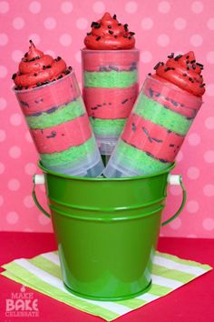 some cupcakes are in a green bucket on a pink table with polka dots