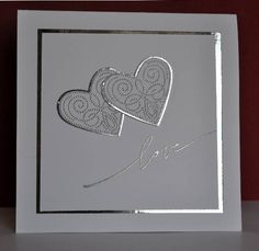 two hearts cut out of paper in a white card with silver foil on the inside