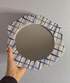 a person holding a mirror in front of a wall