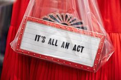 it's all an act sign attached to a red dress