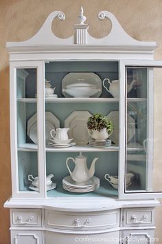 a white china cabinet with dishes on it