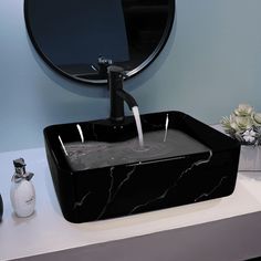 a black square sink in front of a round mirror