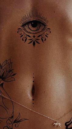 a woman's back with an all seeing eye tattoo on her chest and chain