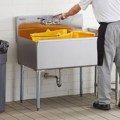 a man standing in front of a sink with yellow bins on the bottom and side