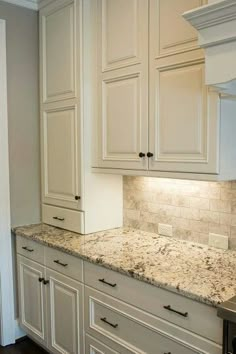 a kitchen with white cabinets and granite counter tops