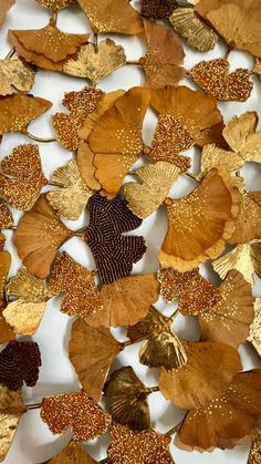 gold and brown leaves are arranged on a white surface