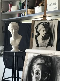 an artist's studio with art work on easel and busturines in the background