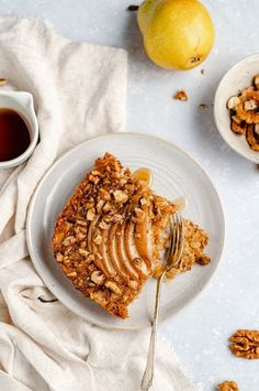 a piece of cake on a plate with a fork and bowl of fruit next to it