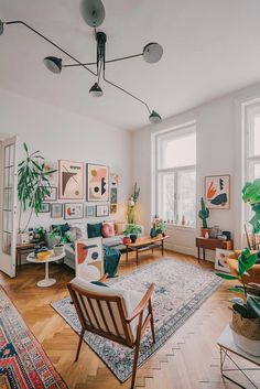 a living room filled with lots of furniture and plants on the wall above it's windows