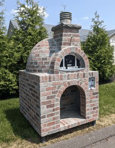 an outdoor brick pizza oven sitting in the grass