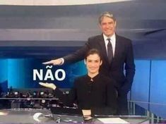 two people are standing in front of a news set with one person pointing at the camera