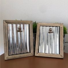 two mirrors sitting on top of a table next to a potted green plant in front of them