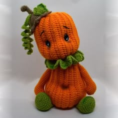 an orange stuffed animal with green leaves on it's head and eyes, sitting in front of a white background