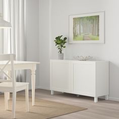 a white dining room table and chairs in front of a painting on the wall above it