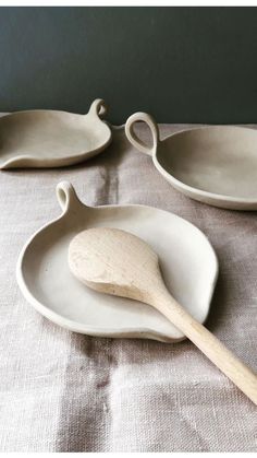 two white dishes with wooden spoons on them