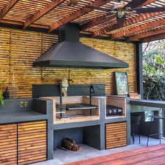 an outdoor kitchen that is built into the side of a building with wood flooring