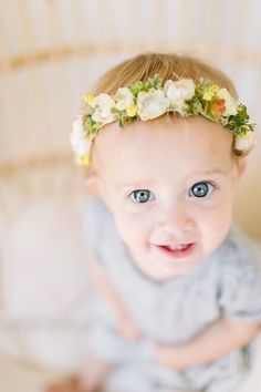 a smiling baby with flowers in her hair