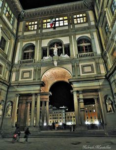 an old building with columns and statues on the front entrance to it at night time