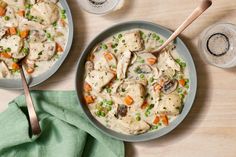 two bowls filled with chicken and dumplings on top of a table next to water glasses