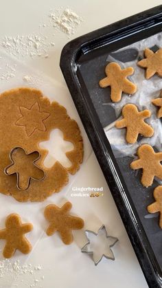 gingerbread cutouts and cookie cutters on a baking sheet