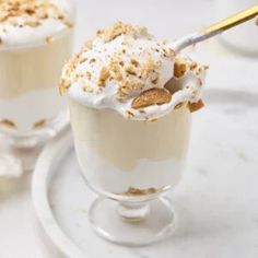 two dessert cups filled with whipped cream and cinnamon sprinkles on a white plate