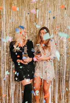 two women standing next to each other in front of confetti