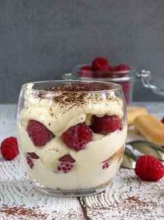 two desserts with raspberries and whipped cream in them on a white table