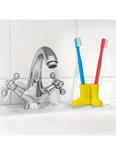 two toothbrushes sitting in a sink next to a yellow holder with blue and red handles