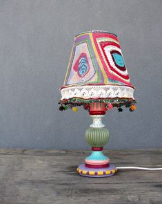 a lamp that is sitting on top of a wooden table next to a gray wall