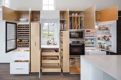 an open pantry in the middle of a kitchen with lots of cupboards and drawers