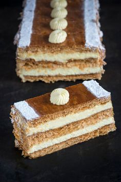 two pieces of cake sitting on top of a black table with white frosting and icing