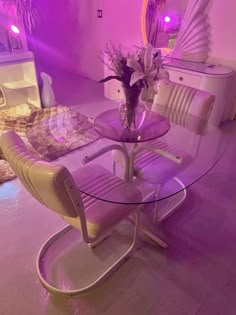 a glass table with two chairs and a vase on it in front of a mirror